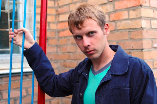 Young stylish man with blonde hair stand near brick wall.