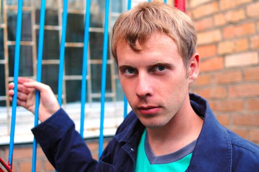 Young stylish man with blonde hair stand near brick wall.