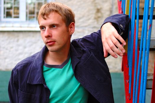 Young stylish man with blonde hair stand near handrail.