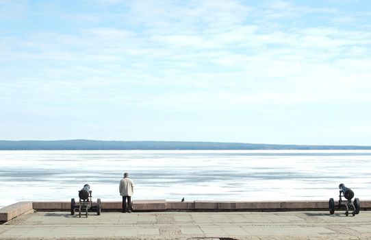 The man, two guns and the pigeon on coast of lake. Quay of Petrozavodsk, Russia            