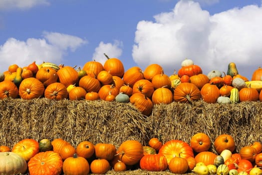 Pumpkins on bales of straw (hay) against the blue cloudy sky