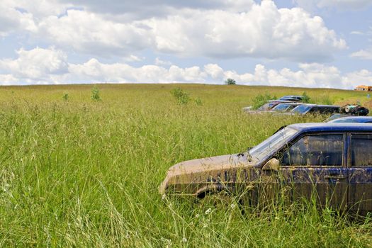 A dirty car standing in a green field