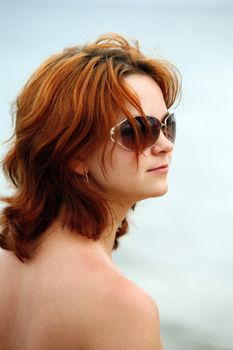 The girl with red hair in solar glasses