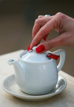 White tea teapot and female hand
