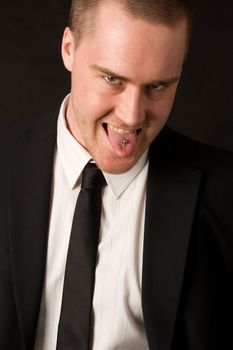 Portrait of a young businessman with tungpiercing on dark background