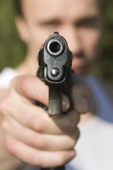 A man holding a pistol and pointing it at the camera.