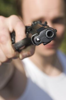 A man holding a gun and pointing it at the camera. 