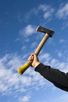 hand with an axe on sky background