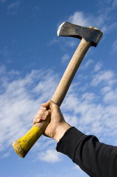 hand with an axe on sky background
