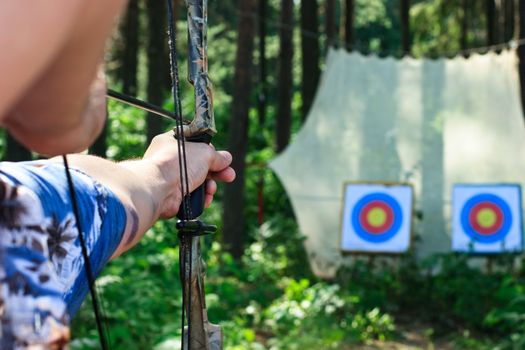 Man aiming bow at targets in summer forest