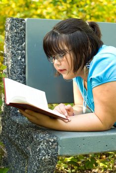 A young girl reading a story book outside