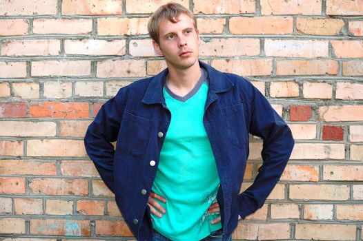 Young stylish man with blonde hair stand near brick wall.