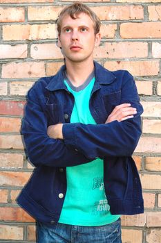 Young stylish man with blonde hair stand near brick wall.