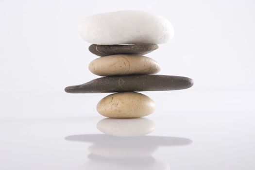 Front view of balancing stones over a white background with reflection