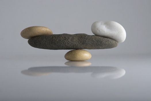 Front view of balancing stones over a white background with reflection