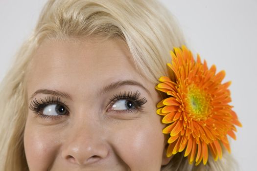 lady with flower in hair looking askance against white background