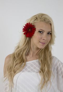 sensual lady with red flower in hair against white background