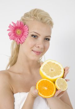 young lady with fruits and pink flower in hair on isolated studio pictures