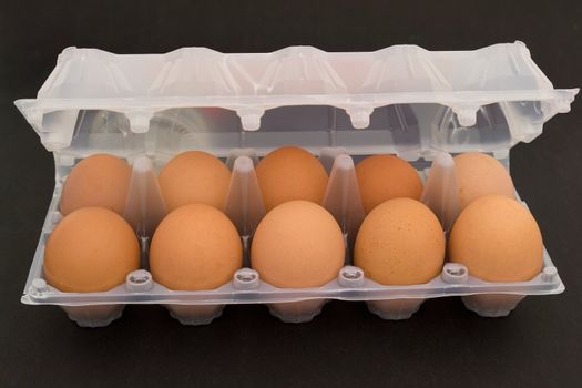 Ten eggs in packing on a black background