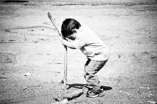 Boy Playing With Stick in the Sand