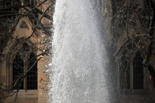 Close up of a large water fountain in front of an old gothic church window