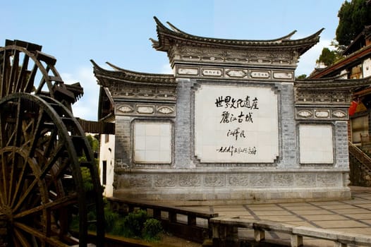 Entrance to old town Suhe in Lijiang city, Yunnan province, China. Historical watermill and gate with name of place.
