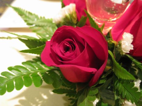 a table decorated with a beautiful red rose and fern leaves 