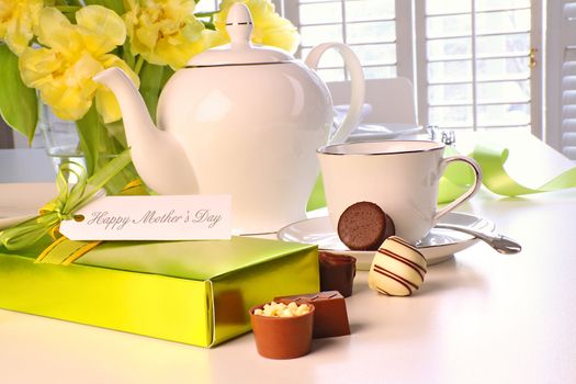 Box of chocolates on table with tea set and tulips