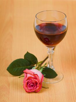 A glass of red wine and rose on the table