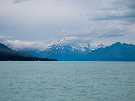 Mount Cook in New Zealand surrounded by clouds with a blue lake