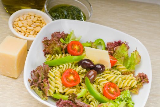 fresh healthy homemade italian fusilli pasta salad with parmesan cheese,pachino cherry tomatoes, black olives and mix vegetables ,dressed with extra-virgin olive oil and pesto sauce