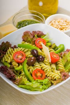 fresh healthy homemade italian fusilli pasta salad with parmesan cheese,pachino cherry tomatoes, black olives and mix vegetables ,dressed with extra-virgin olive oil and pesto sauce