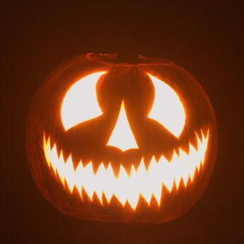 Carved Halloween pumpkin glowing in the dark.