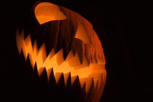 Carved Halloween pumpkin glowing in the dark.