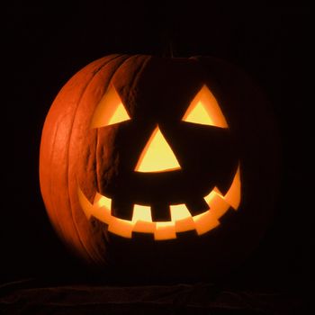 Carved Halloween pumpkin glowing in the dark.
