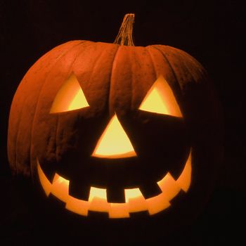 Carved Halloween pumpkin glowing in the dark.