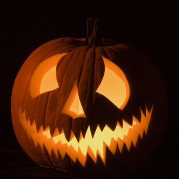 Carved Halloween pumpkin glowing in the dark.