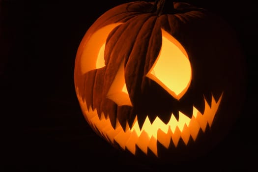 Carved Halloween pumpkin glowing in the dark.