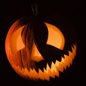 Carved Halloween pumpkin glowing in the dark.