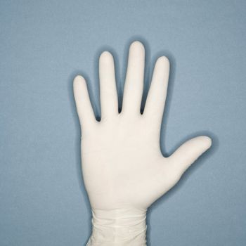 Hand with five fingers extended wearing white rubber glove.