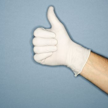 Hand wearing white rubber glove giving the thumbs up signal.