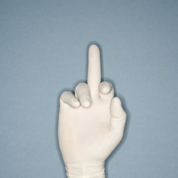 Hand wearing white rubber glove with middle finger extended making profane gesture.