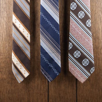 Three retro ties against wood paneling.