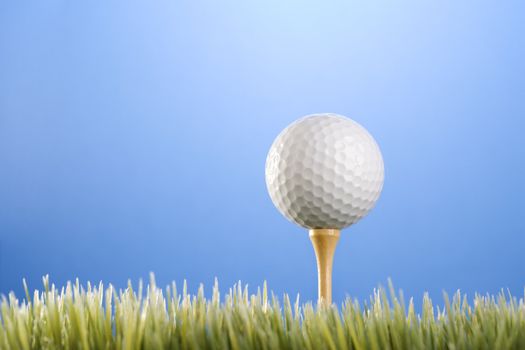 Studio shot of a golfball on a tee in grass.