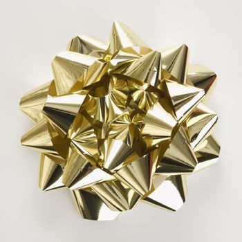 Still life of big shiny gold Christmas bow.