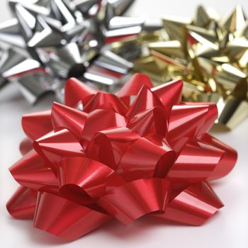 Still life of big shiny red, gold and silver Christmas bows.