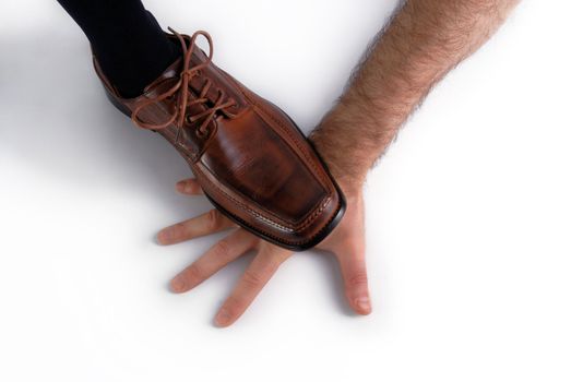 Shoe of a businessman showing his power by crushing the hand of another man