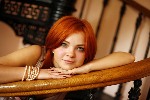 Portrait of the girl with red hair in an interior