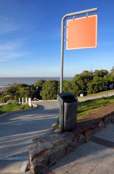 Street with an empty signage. Suitable for insert text, image or design. Vegetation, beach and blue sky on the background.