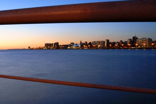 Coastline landscape of modern buildings at sunset behind bridge railing